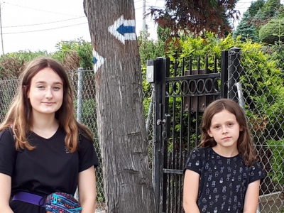 Dwie dziewczynki siedzą pod drzewem. Obie ibrane w czarne koszulki